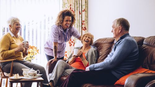 Vrouwen en man lachen in woonkamer Vrouwen en man lachen in woonkamer