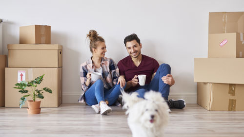 Jong stel zit tussen verhuisdozen na het kopen van hun eerste huis Jong stel zit tussen verhuisdozen na het kopen van hun eerste huis