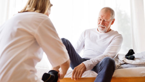 Vrouw helpt man met sokken aandoen Vrouw helpt man met sokken aandoen