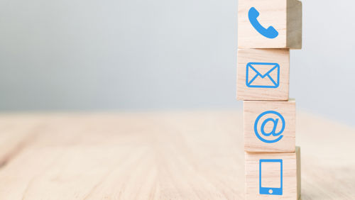 Tafel met blokken met daarop iconen van telefoon en mail Tafel met blokken met daarop iconen van telefoon en mail