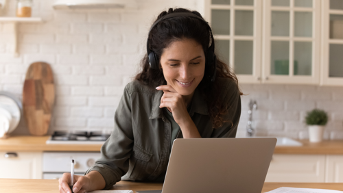 Vrouw volgt een online webinar aan de keukentafel Vrouw volgt een online webinar aan de keukentafel