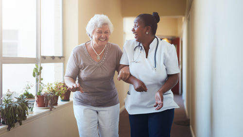 Vrouw lacht naar oude vroeg in ziekenhuisgang Vrouw lacht naar oude vroeg in ziekenhuisgang